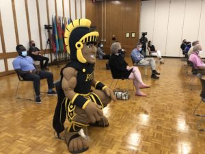 The FTCC Trojan mascot sitting on the floor of a lecture hall, socially distanced from others in the audience