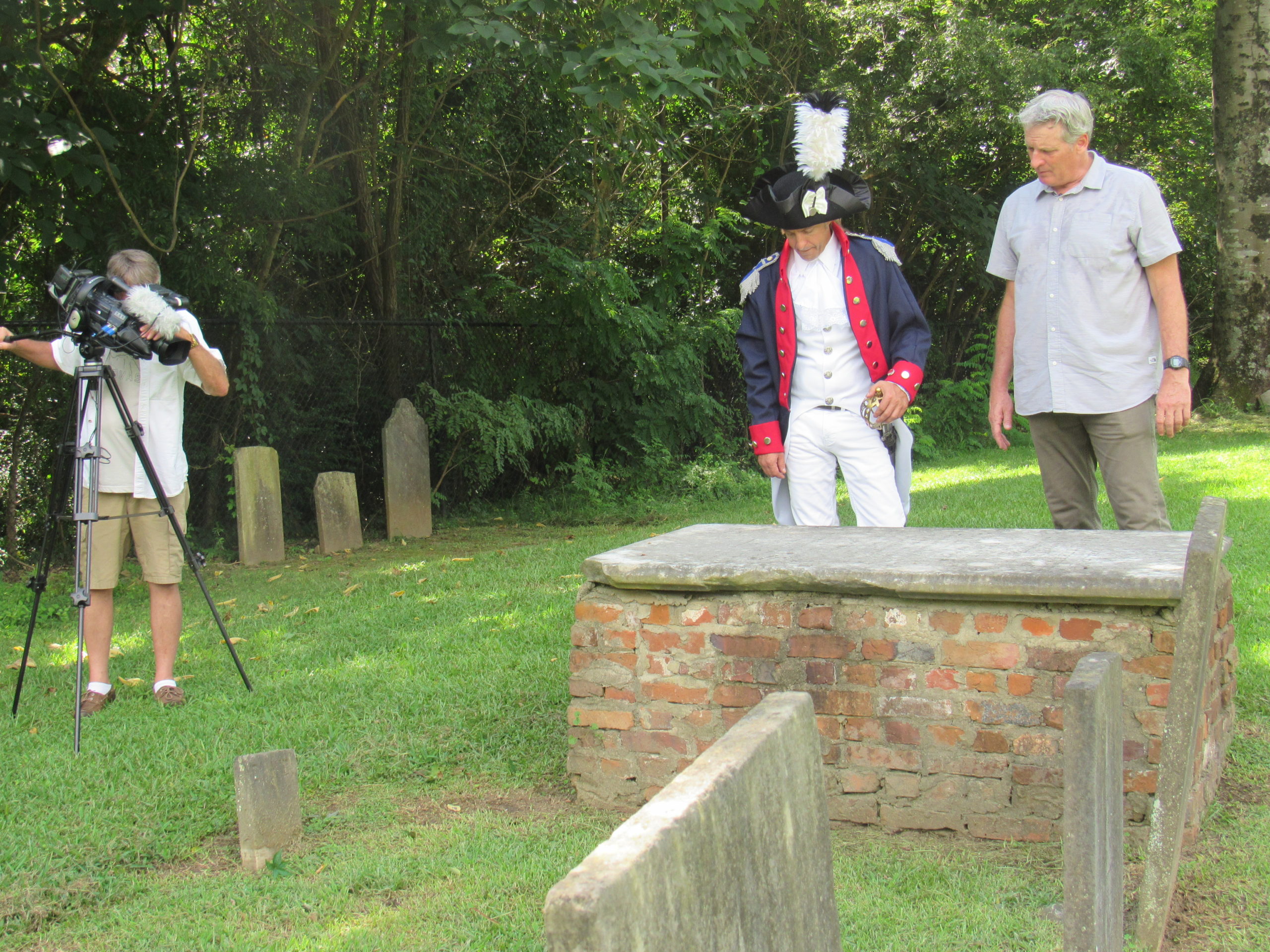 A videographer, Lafayette reenactor, and director at a raised grave