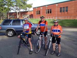 A photo of three men in cycling gear standing with their bicycles in a parking lot. "Gaston and friends” from the St. Avold area in France came to do some cycling in America in 2013. The Lafayette Society connected them with Cross Creek Cycling Club and both groups took a 40-mile ride around Fayetteville.