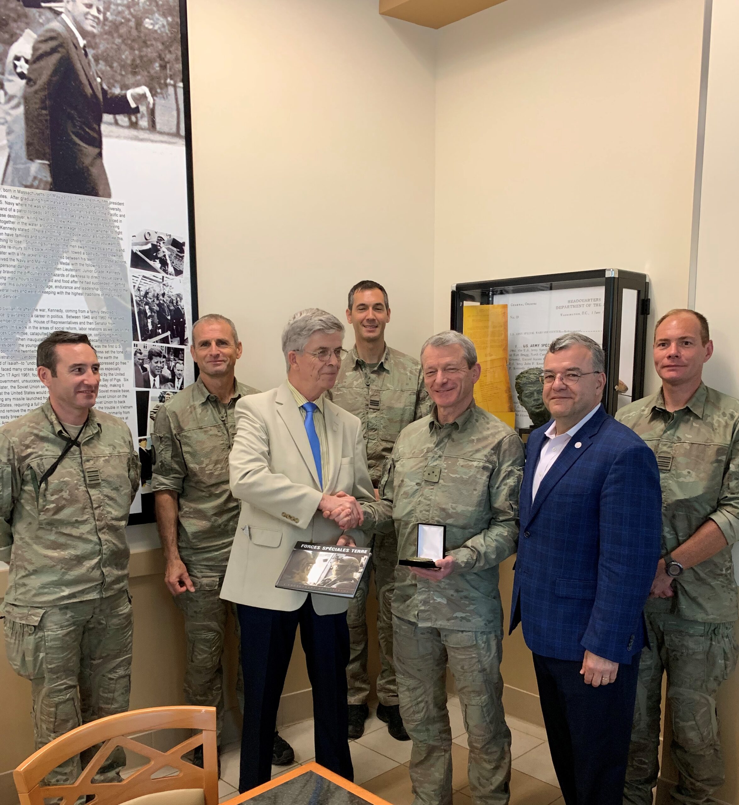 A photo of a group of men, some in suits and some in army uniforms, with two of them shaking hands. In 2019 Members of the Lafayette Society attended a lunch at Ft Bragg with General Thierry Ducret, commander of the French special forces.