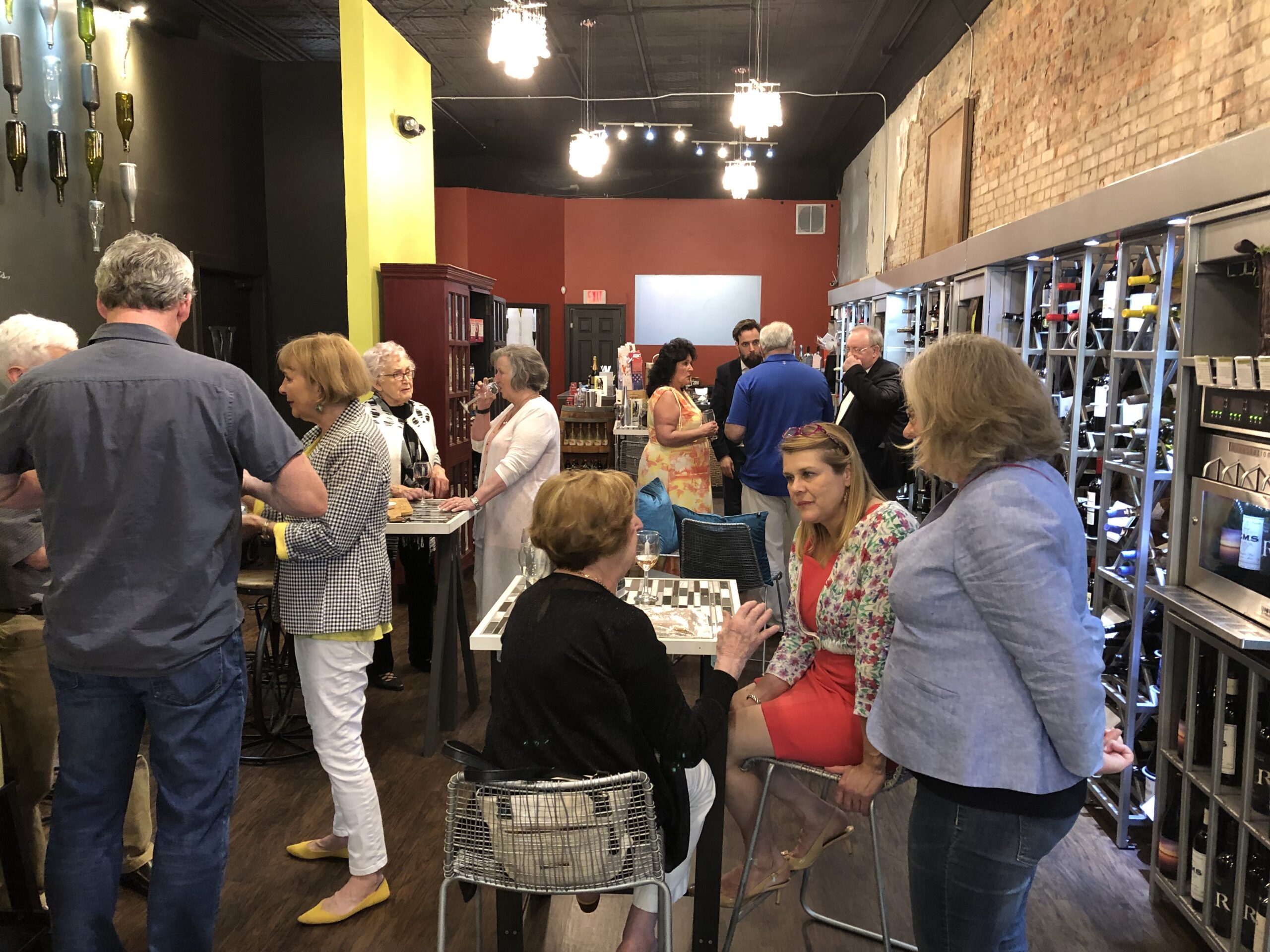 A picture of a group of people socializing around tables with wine dispensers in the background. In 2019 the Lafayette Society held a reception for the St Avold delegation at the Wine Cafe.